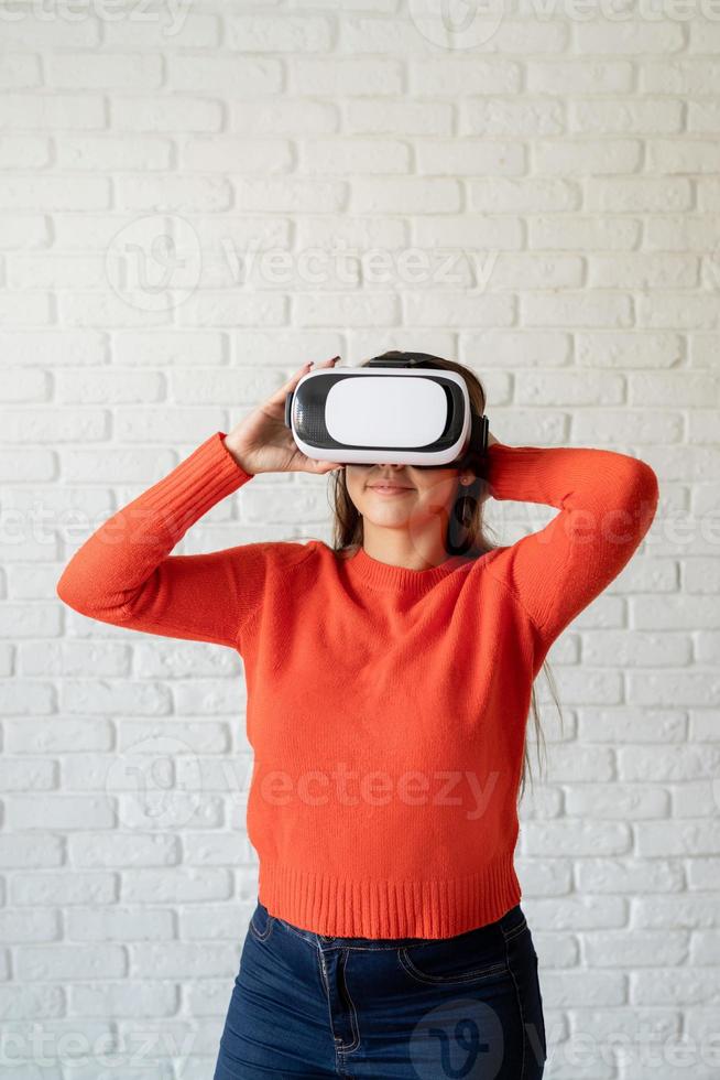 sorriso mulher feliz obtendo experiência usando óculos vr-headset de realidade virtual em casa gesticulando com as mãos foto