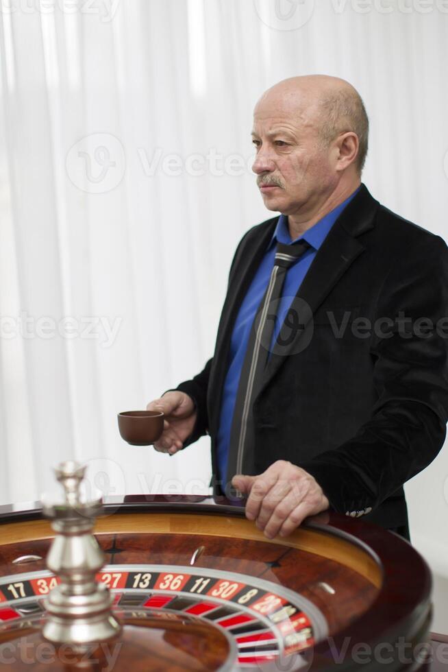 elegante idosos homem dentro uma cassino com uma copo do café foto