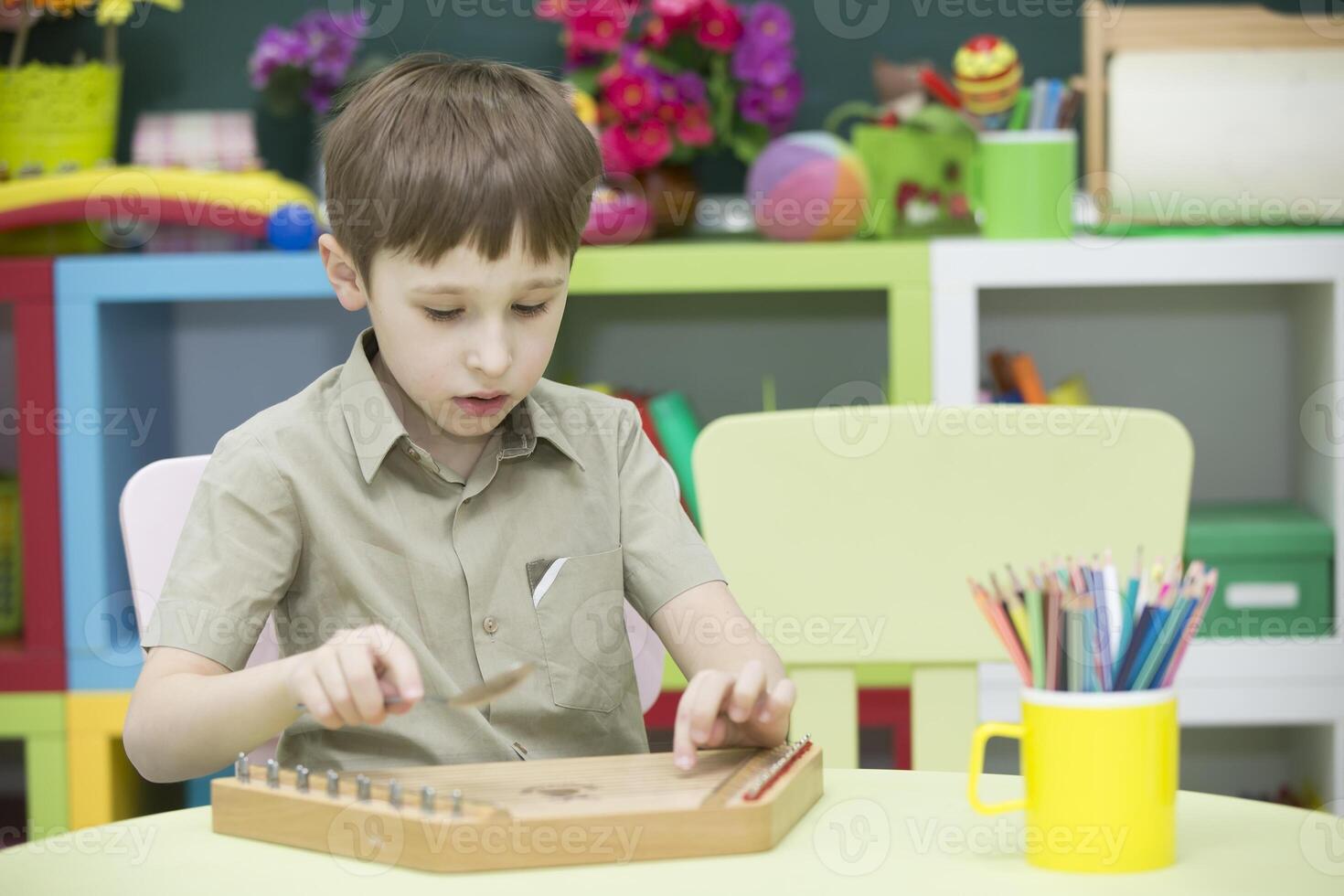 uma criança com uma musical instrumento. Garoto aprender para jogar dulcimer foto