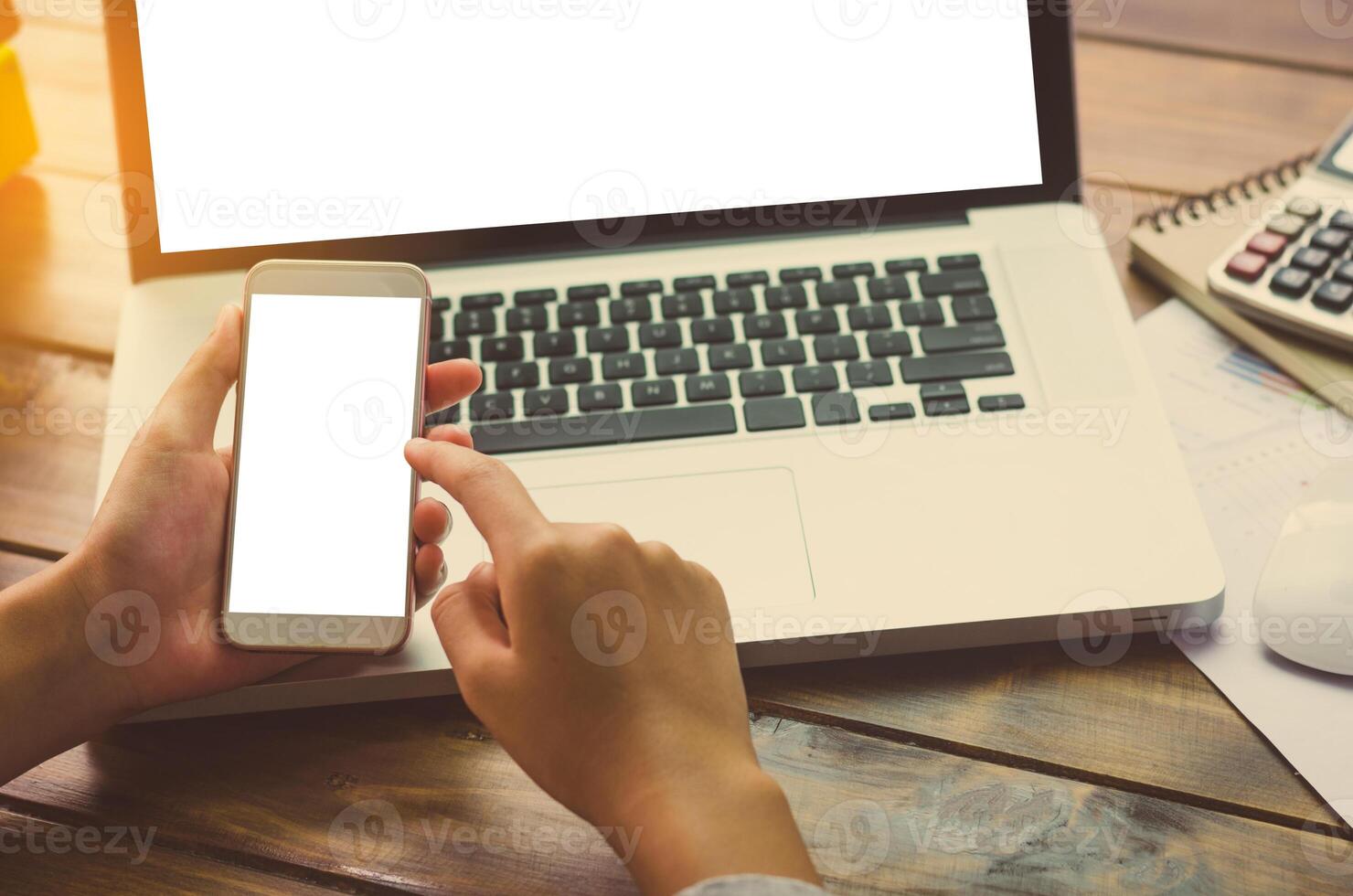 mão segurando Smartphone para trabalhando em computador portátil foto