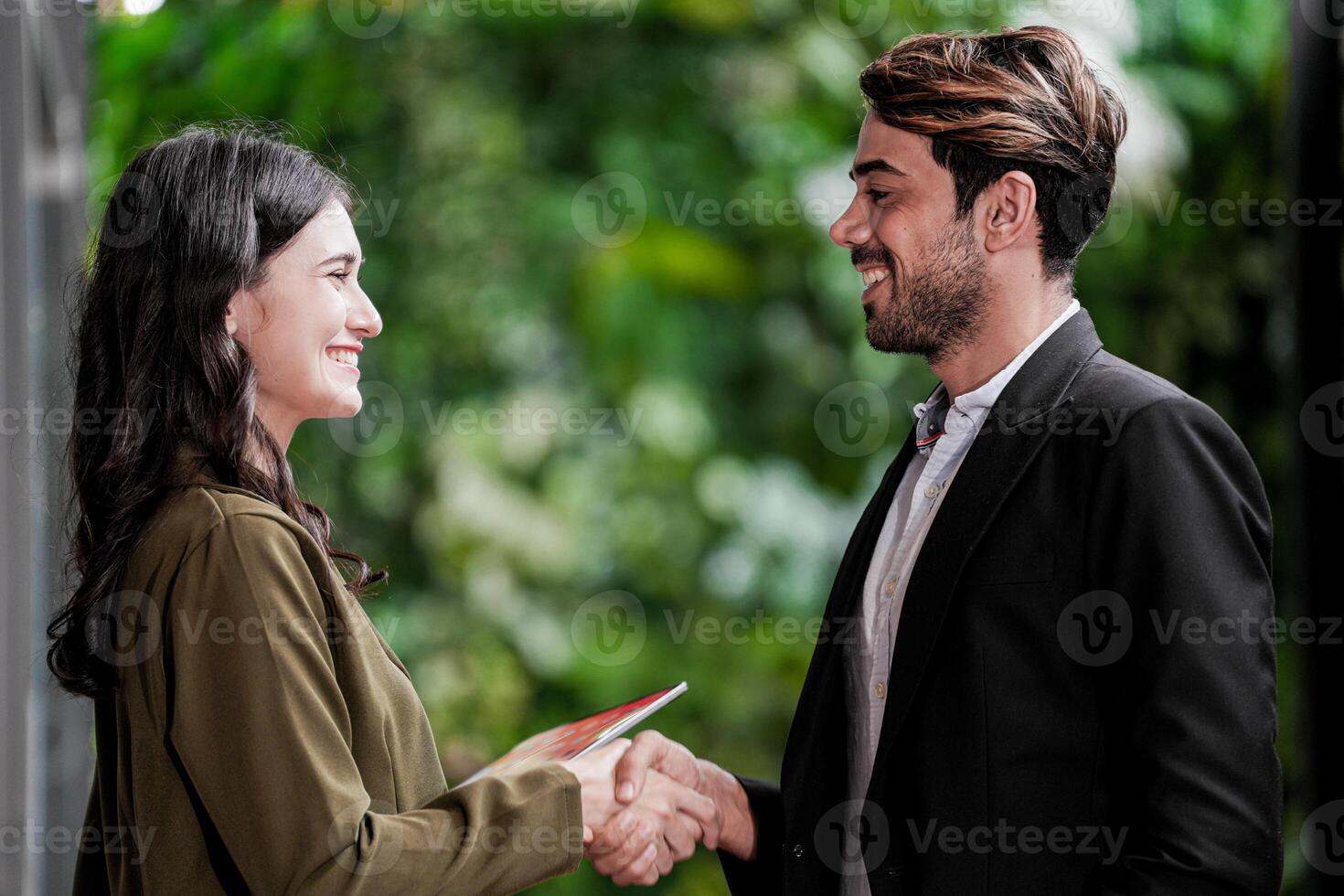 homem de negocios e casual empresária tremendo mãos ao ar livre. dois jovem multicultural colegas de trabalho acordo para sucesso. fundo do verde parede natureza árvores foto