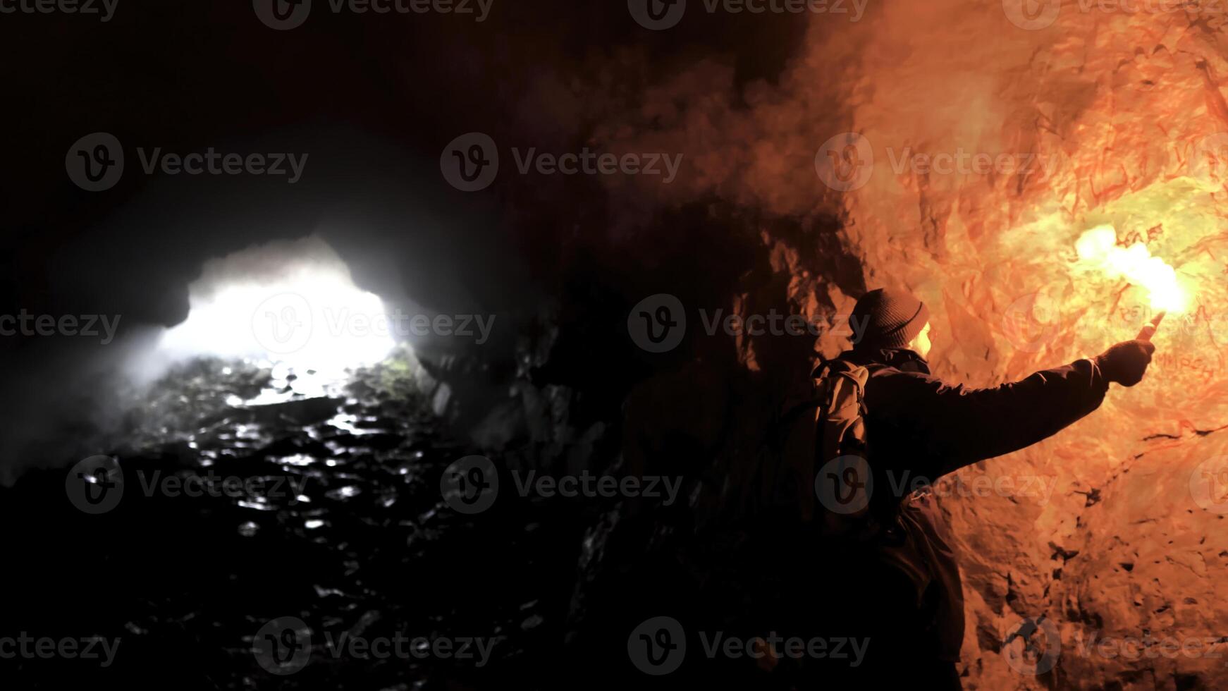 solitário homem com uma vermelho queimando sinal flare dentro uma Sombrio caverna olhando para a buraco, turismo conceito. estoque imagens de vídeo. masculino explorando subterrâneo caverna. foto