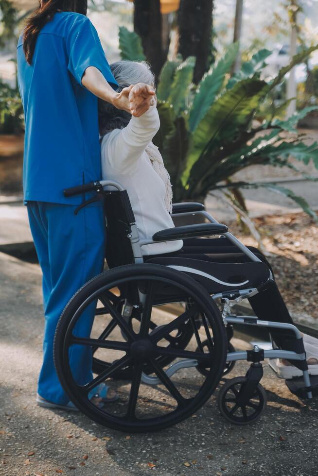 uma enfermeira levar Cuidado uma Senior masculino em cadeira de rodas dentro dele jardim às casa foto