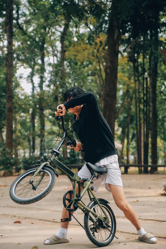 bonito feliz jovem homem com bicicleta em uma cidade rua, ativo estilo de vida, pessoas conceito foto