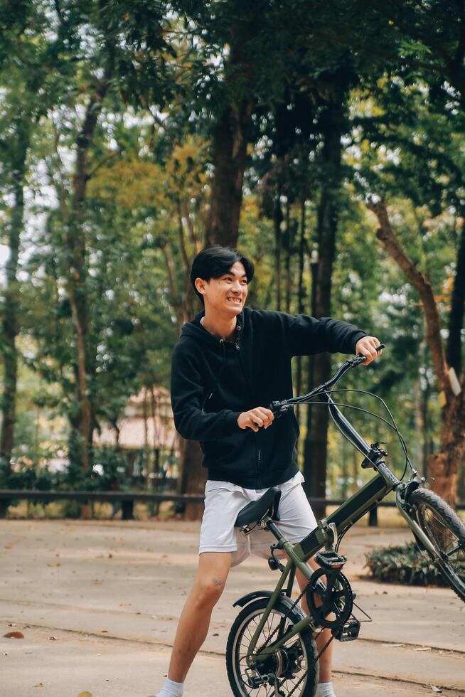 bonito feliz jovem homem com bicicleta em uma cidade rua, ativo estilo de vida, pessoas conceito foto