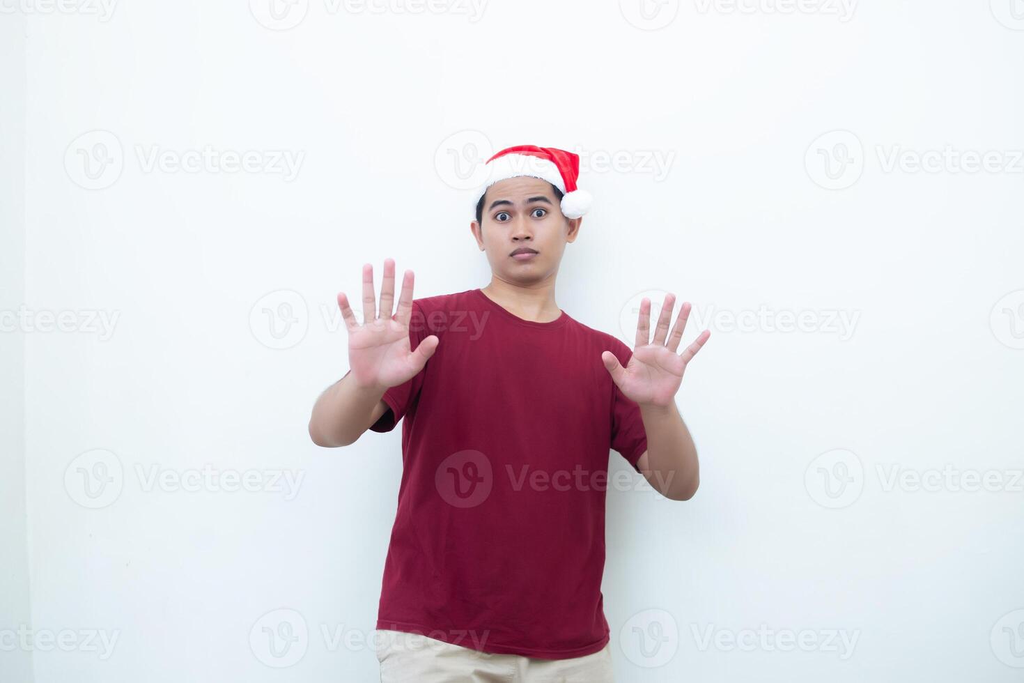 jovem ásia homem vestindo uma santa claus chapéu expressando choque e falta de vontade isolado de uma branco fundo para visual comunicação foto