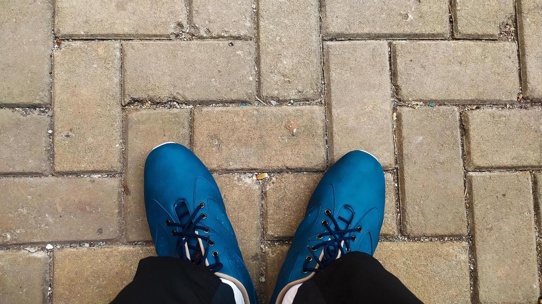 uma azul sapato descansos em uma cor de creme em forma de tijolo rua foto