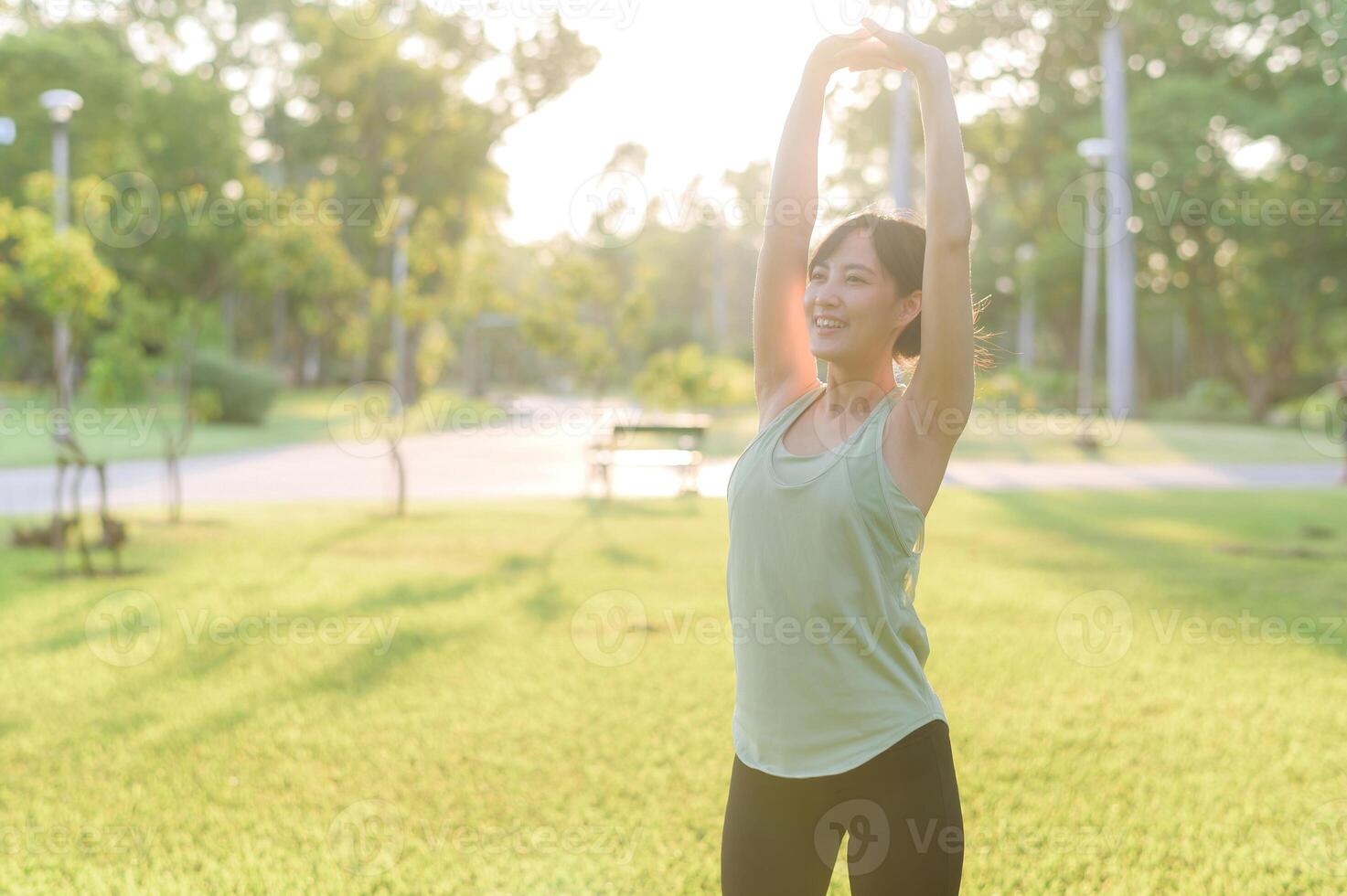 fêmea corredor. em forma jovem ásia mulher com verde roupa de esporte alongamento músculo dentro parque antes corrida e desfrutando uma saudável ar livre. ginástica corredor menina dentro público parque. bem estar ser conceito foto