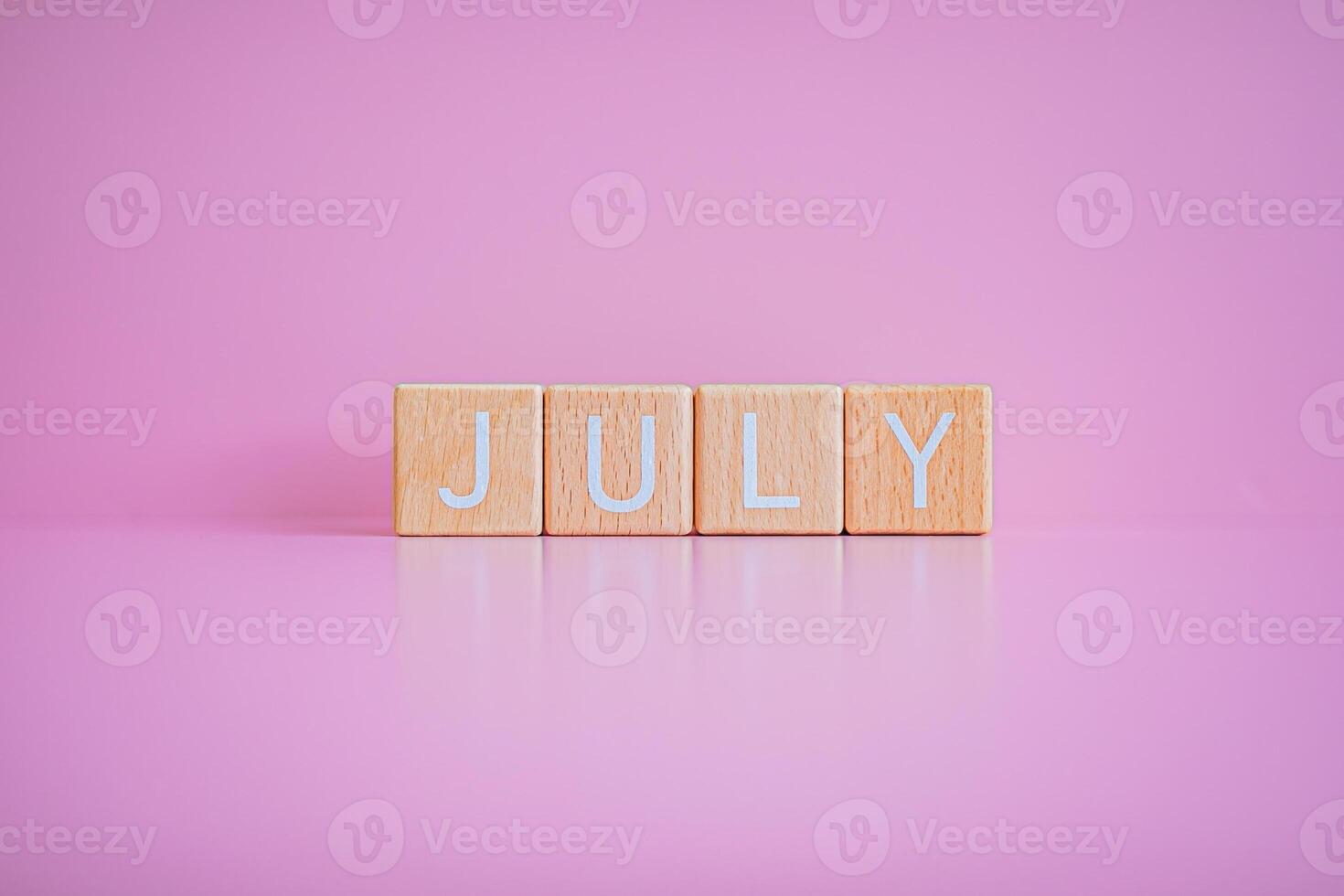 de madeira blocos Formato a texto Julho contra uma Rosa fundo. foto