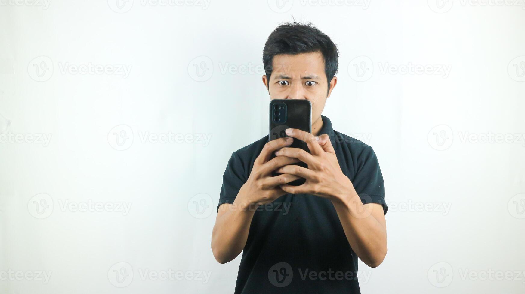 ásia homem com uma sério expressão é jogando uma jogos em dele célula telefone. foto