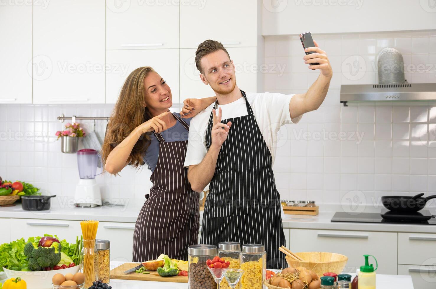 jovem casal amante cozinhando juntos dentro a cozinha às lar. feliz casal levando selfie com Smartphone. foto