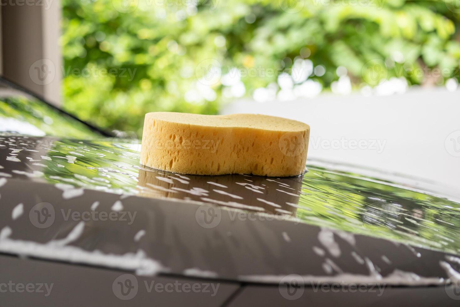 carro limpeza e lavando com amarelo esponja e espuma Sabonete foto