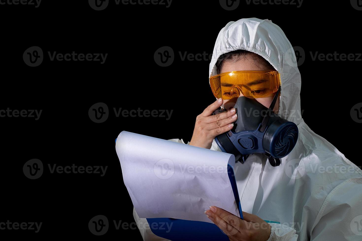 mulher segura pasta de arquivo de relatório em roupa de proteção química branca e máscara antigas com óculos amarelos em fundo preto, cientista mulher em traje de segurança foto