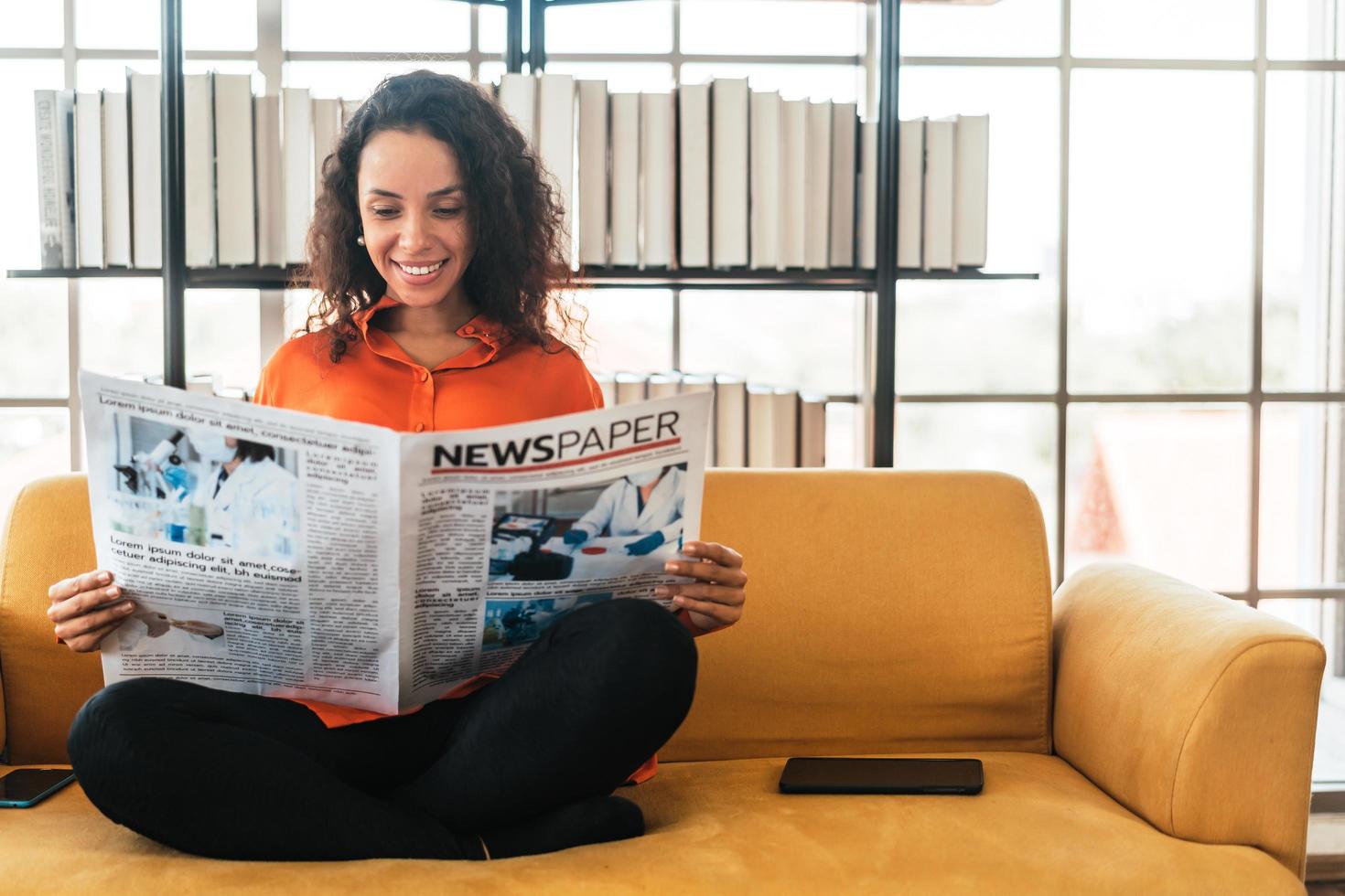 mulher da américa latina lendo jornal no sofá foto