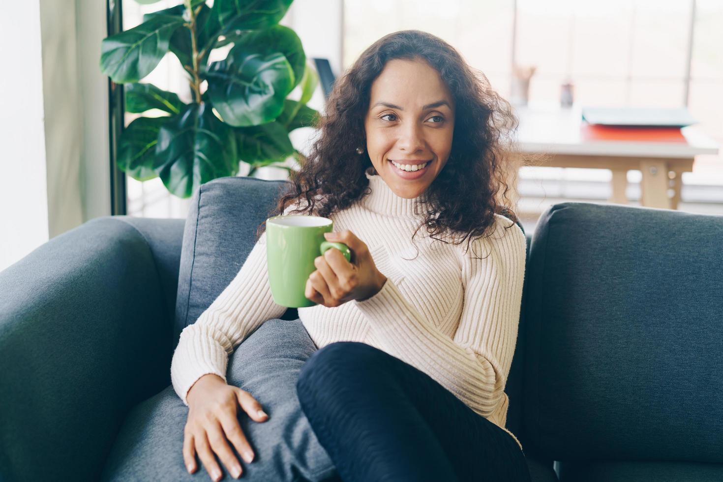 mulher latina tomando café no sofá foto