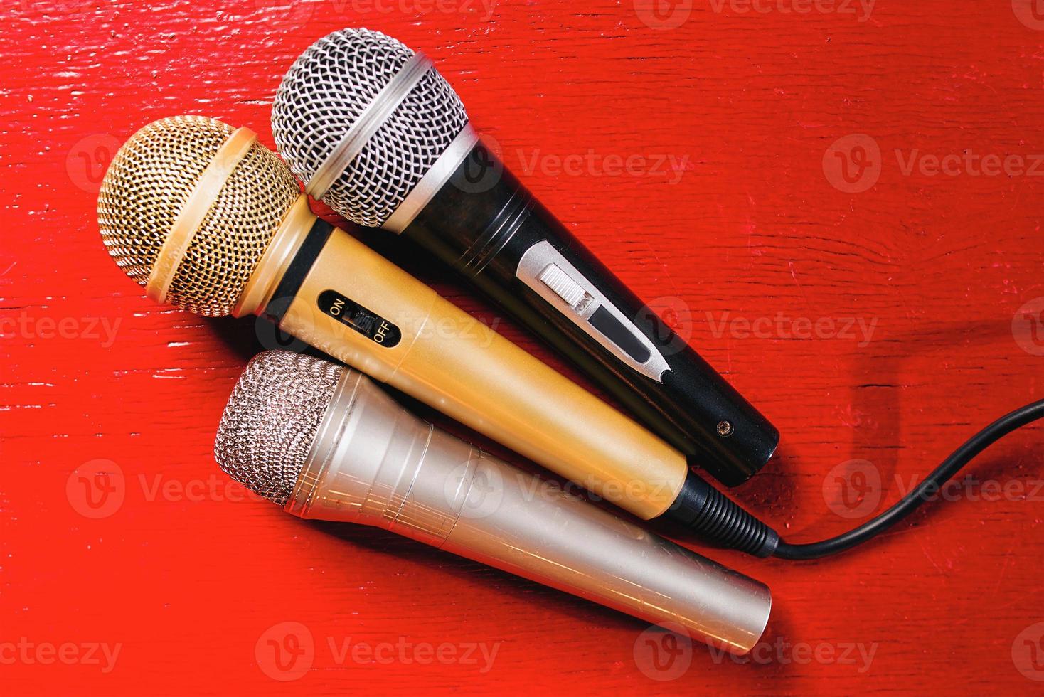 microfones de ouro, prata e bronze em fundo vermelho de madeira foto