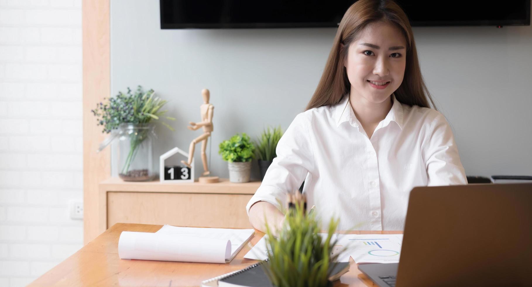 retrato de freelancer jovem asiática está trabalhando em um tablet de computador em um escritório moderno. fazendo relatório de análise contábil, dados de investimentos imobiliários, conceito de sistemas financeiros e fiscais foto