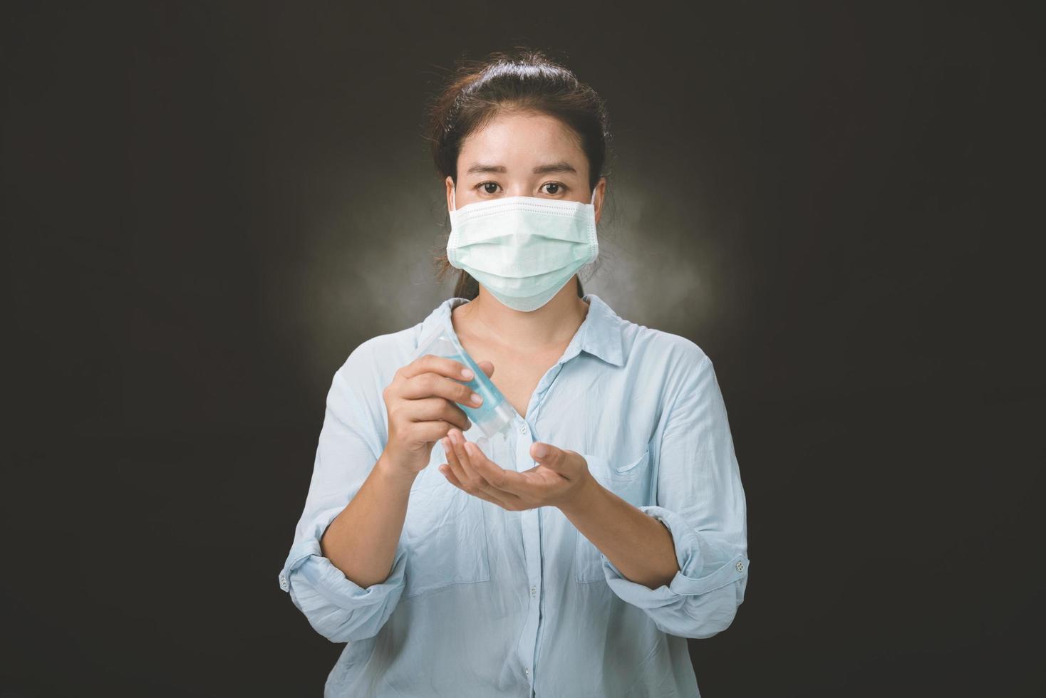 a foto de uma garota no estúdio usando máscara de proteção contra o coronavírus resistente à infecção e limpando as mãos com gel desinfetante.
