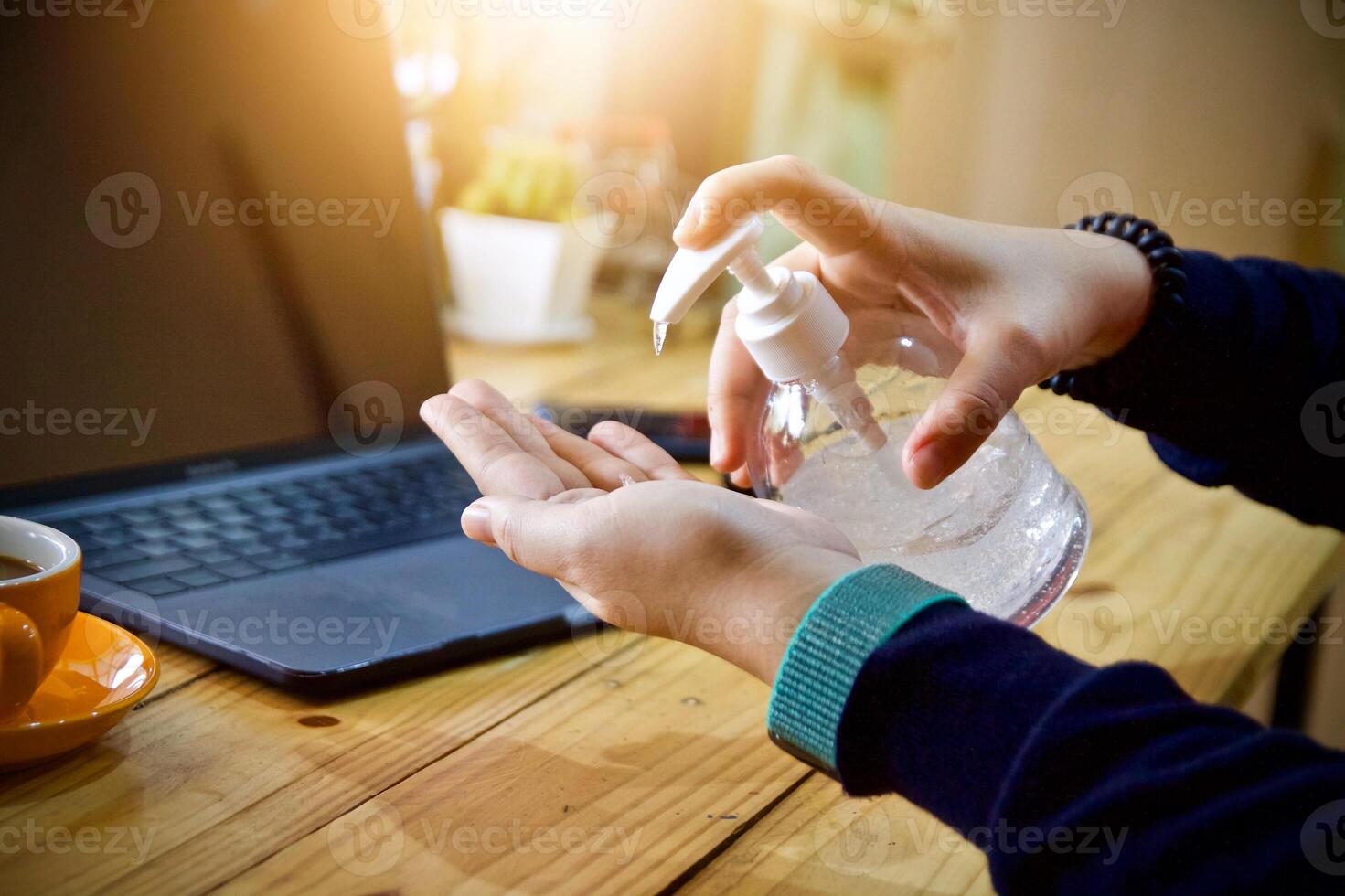 mulheres usando computador portátil trabalhando limpar \ limpo mãos com álcool e beber café copo quente dentro a manhã foto