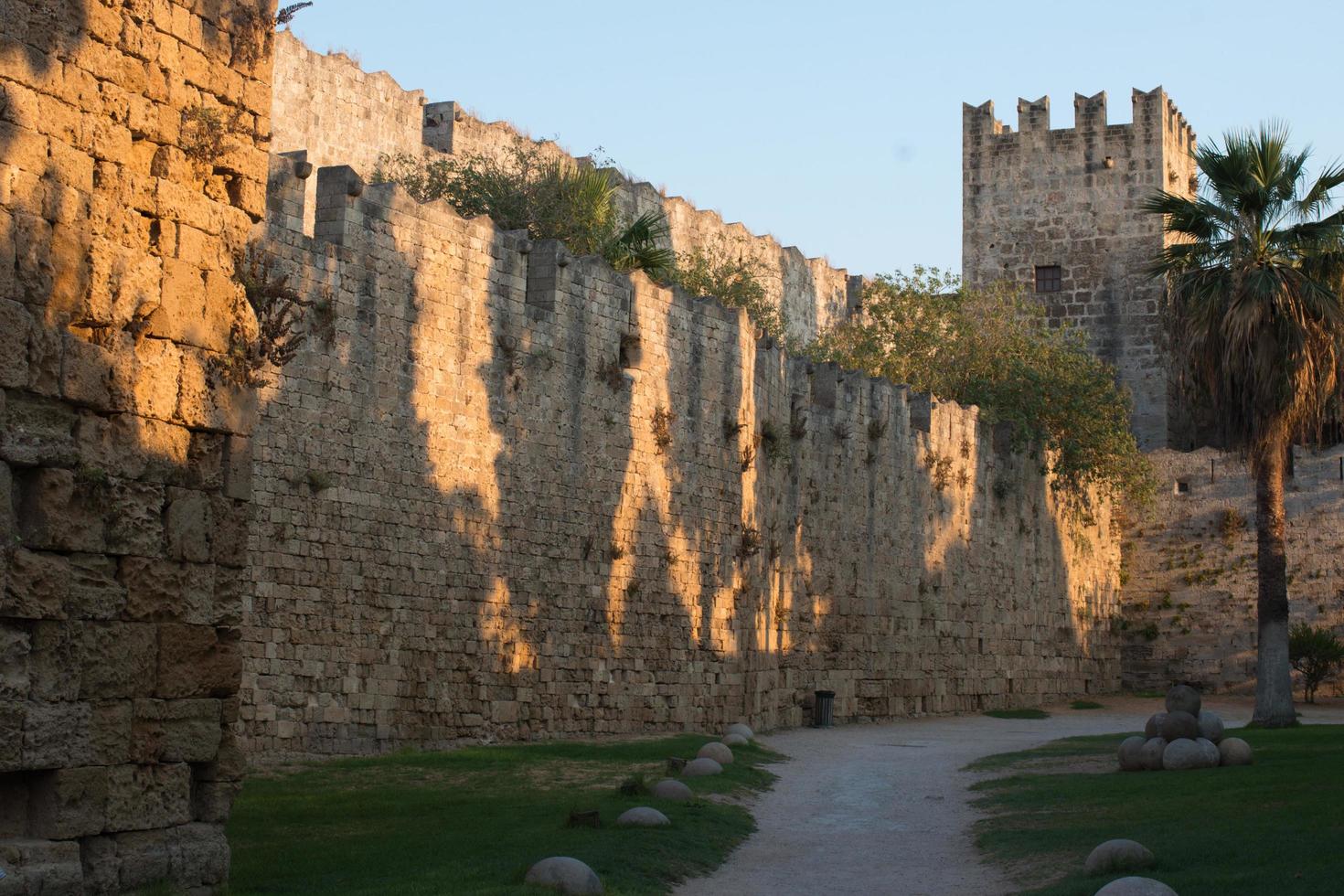 fortificações da cidade de rhodes. velha torre de pedra e palmeira ao pôr do sol. belo marco. Dodecaneso, Grécia. foto