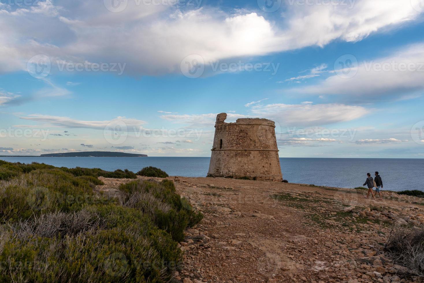 casal caminhando na torre de vigia de sa savina, na ilha de formentera, nas ilhas baleares, na espanha. foto