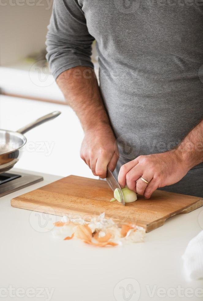 close-up de homem cortando cebola em uma placa de madeira foto