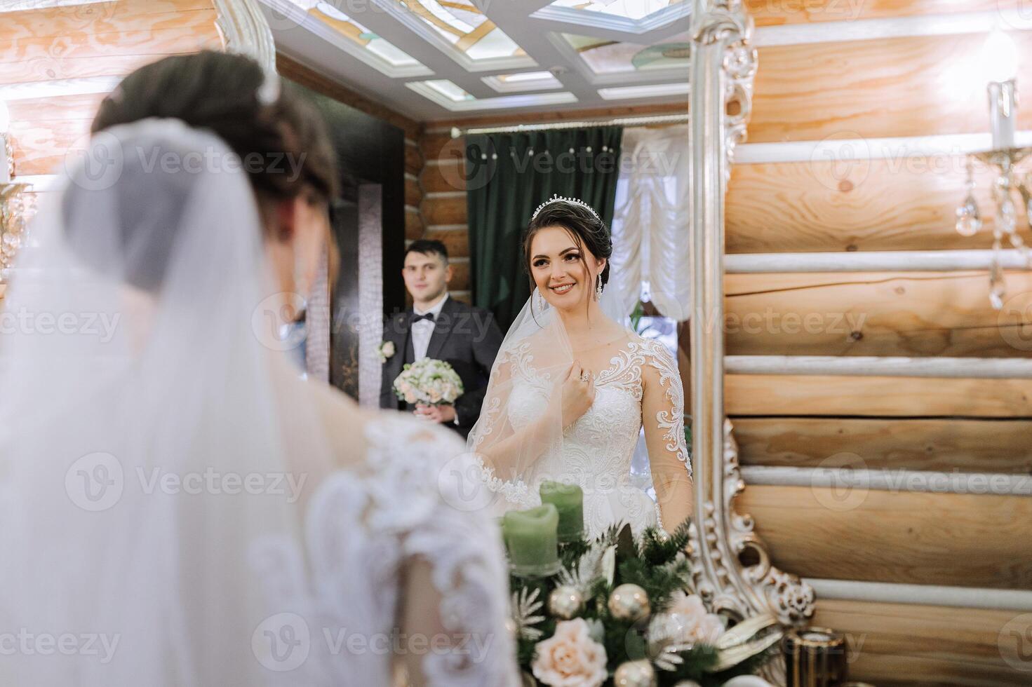 elegante morena noiva poses dentro uma branco vestir perto a espelho. retrato do a noiva, Casamento Maquiagem e Penteado, Casamento moda. lindo noiva dentro uma véu. foto