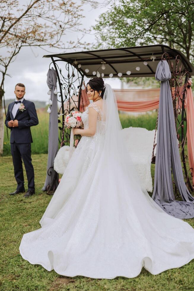 uma lindo jovem noiva, dentro uma verão parque, anda em adiante do dela noivo. lindo Casamento branco vestir. anda em dentro a parque. uma feliz e amoroso casal. foto