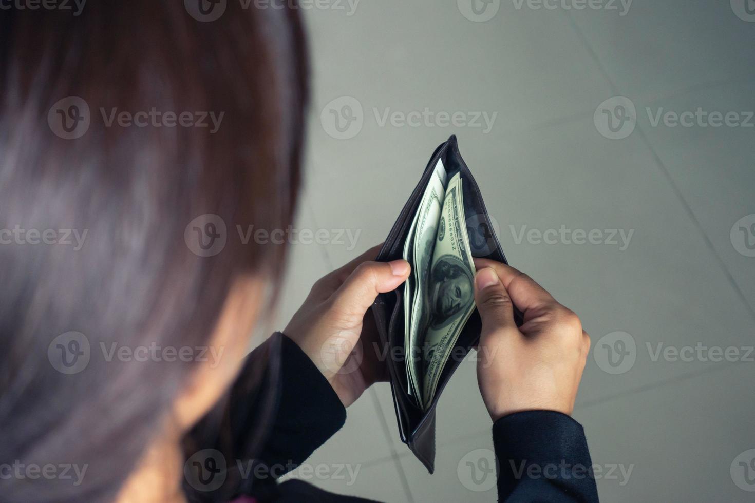 mulher tirando notas de dólar da carteira foto