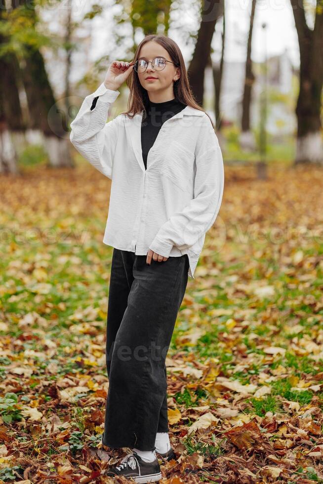 vertical foto. lindo despreocupado jovem Adolescência menina dentro casual roupas. retrato do uma lindo menina contra a fundo do natureza com uma borrado fundo. foto