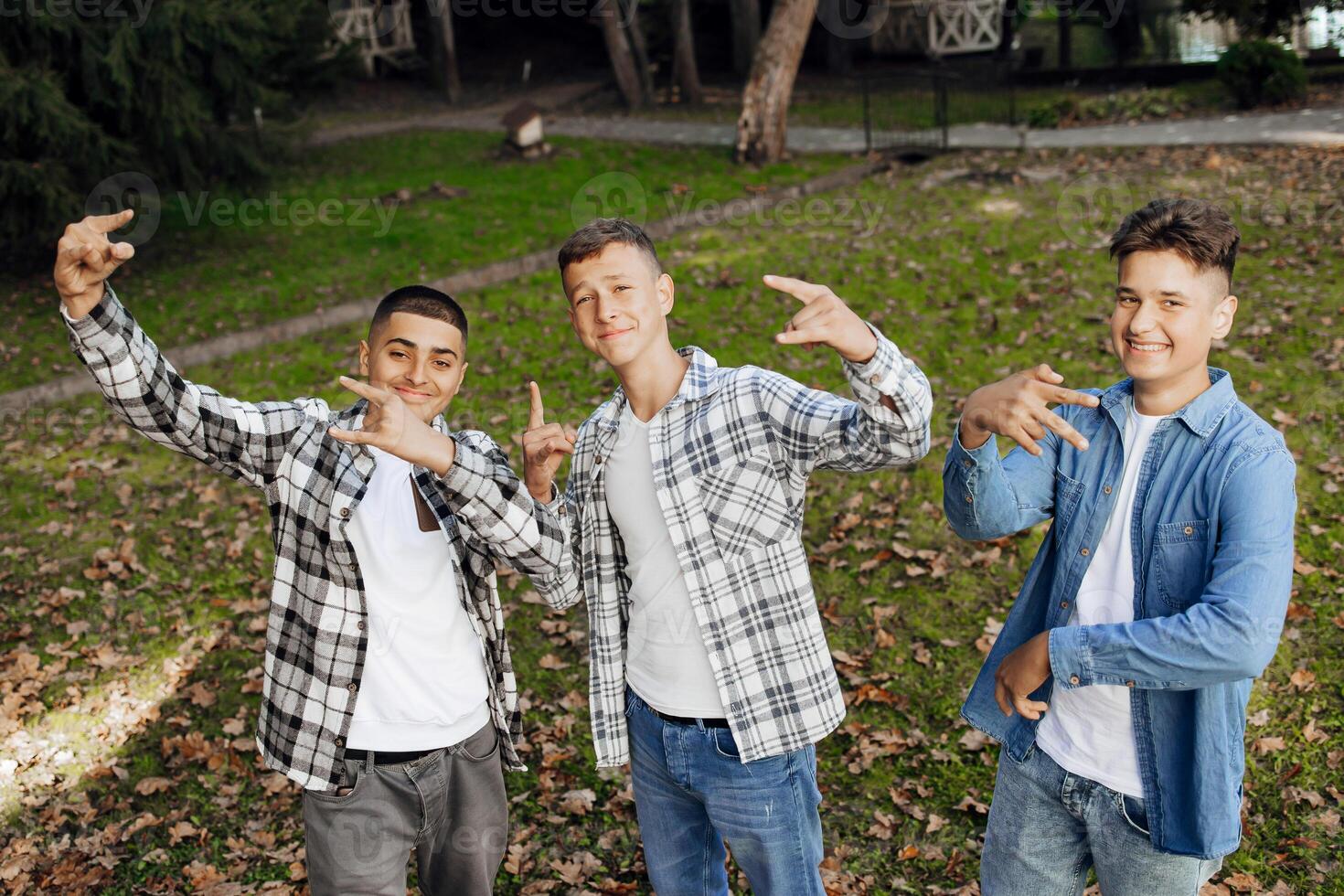 três Adolescência Rapazes, posando dentro natureza, alegria, corrida e tendo Diversão. Adolescência colegas de classe estão em repouso contra a fundo do a outono floresta. foto