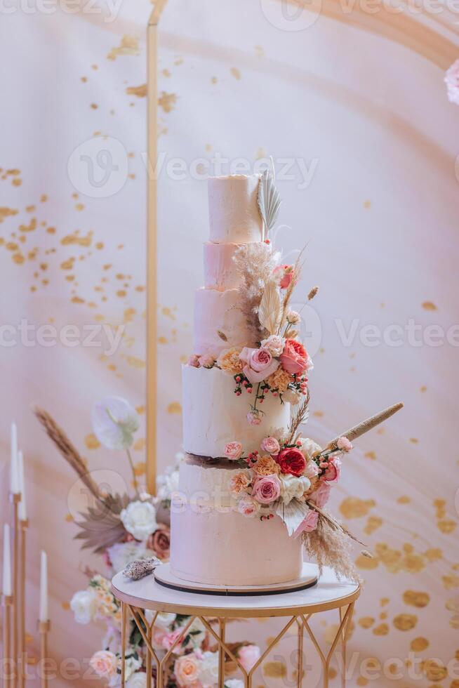 uma multicamadas Casamento bolo dentro a banquete salão, decorado com fresco flores preparação para a Casamento celebração. corte a Casamento bolo. foto