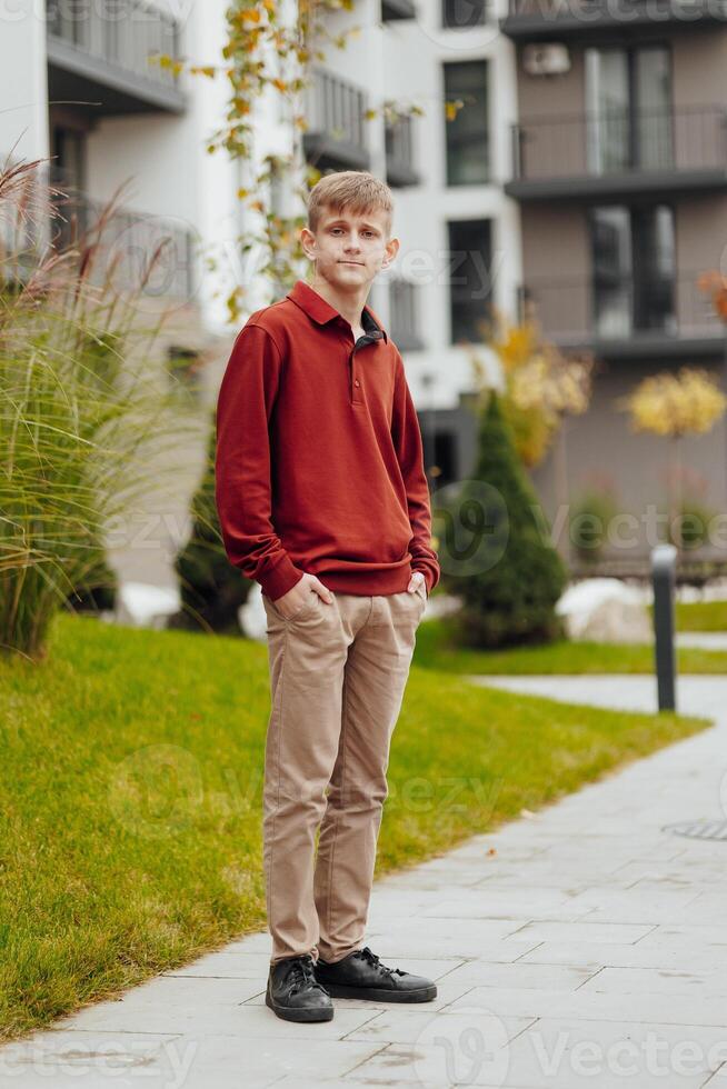 vertical fechar-se retrato do uma adolescente dentro casual roupas. feliz sorridente adolescente dentro outono parque dentro luz solar. uma lindo criança parece às a Câmera dentro natureza. foto