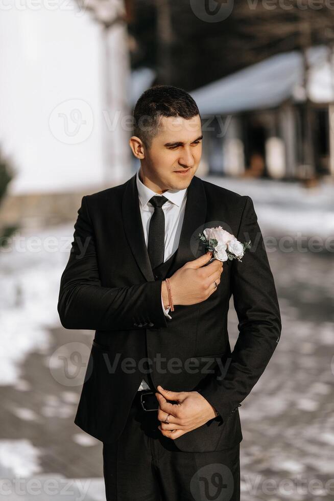 retrato do uma bonito e viril noivo dentro uma Preto terno com uma gravata. noivo dentro natureza dentro a inverno temporada. foto
