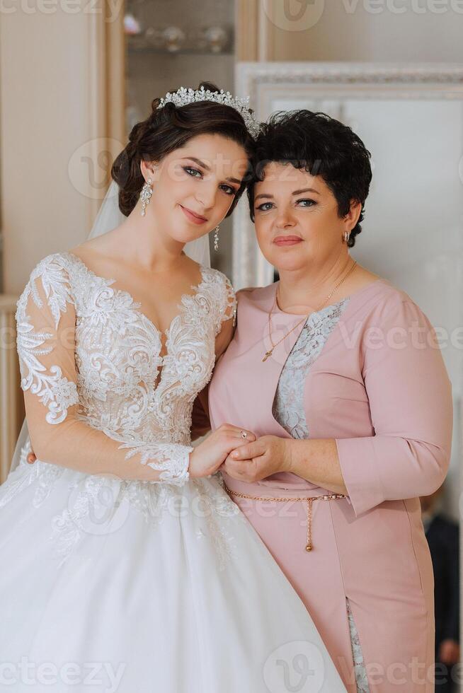 uma lindo e feliz mãe e dela filha, a noiva, estão em pé Próximo para cada outro. a melhor dia para pais. concurso momentos às a casamento. foto