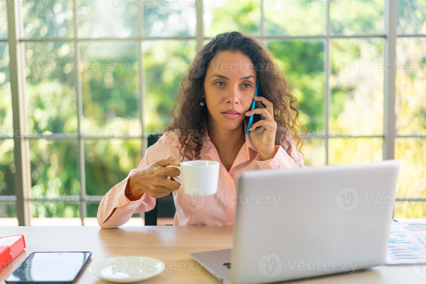 mulher latina trabalhando com uma xícara de café na área de trabalho foto