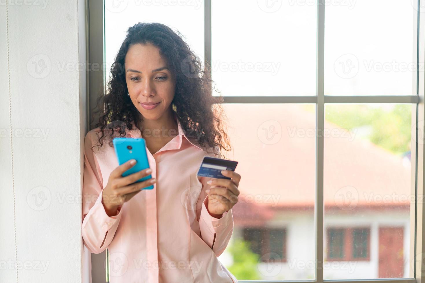 linda mulher latina usando smartphone com cartão de crédito foto