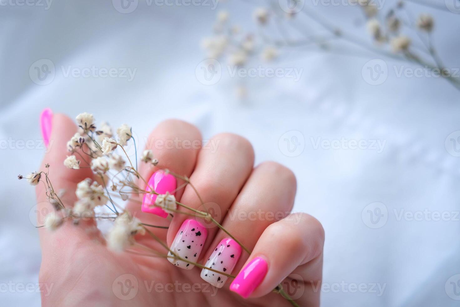 mulheres mãos com uma elegante Rosa manicure aguarde seco flores dentro seus mãos. Primavera - verão unha Projeto foto