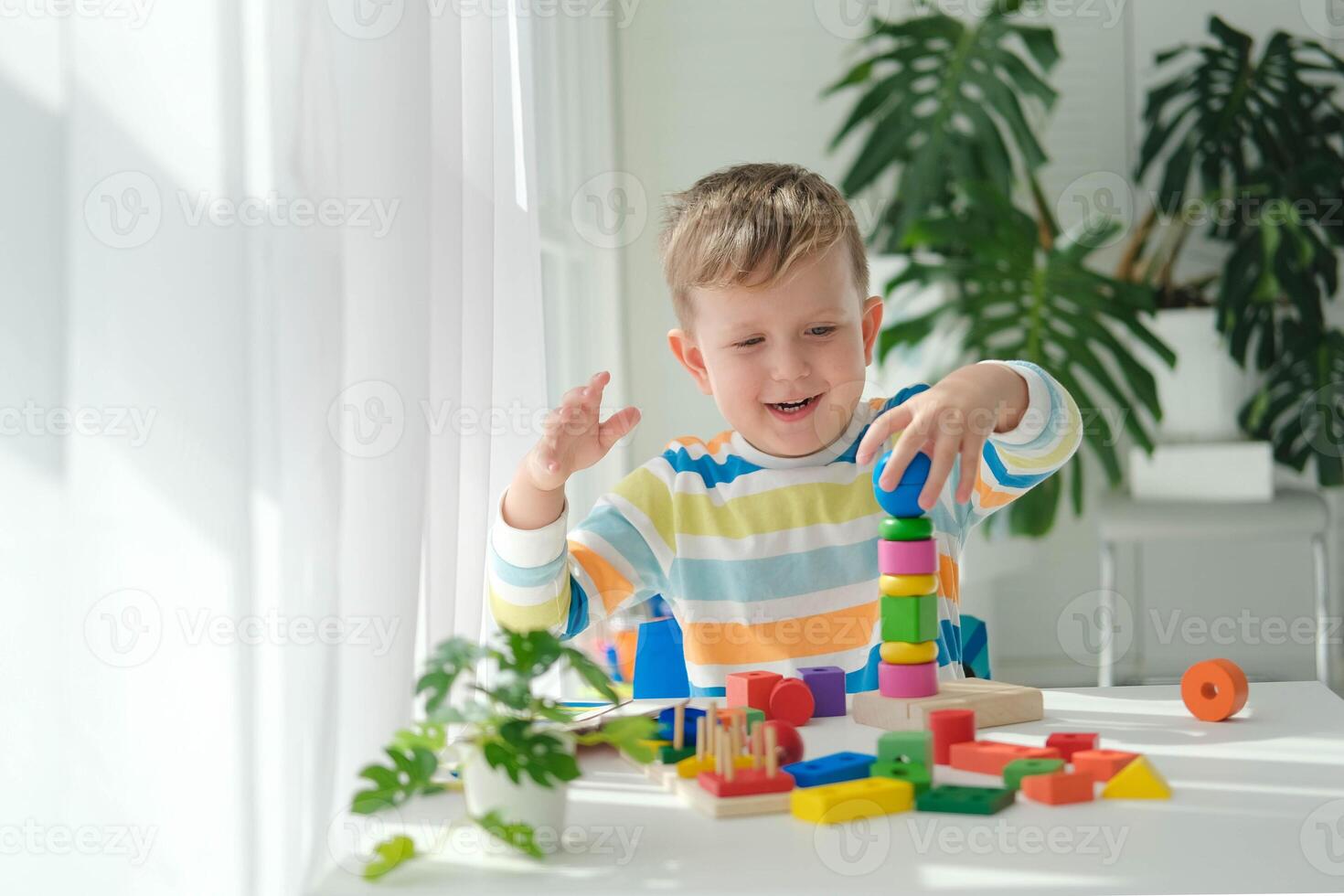 uma pequeno Garoto tocam com de madeira brinquedos e constrói uma torre. educacional lógica brinquedos para crianças. montessori jogos para criança desenvolvimento. crianças de madeira brinquedo. foto