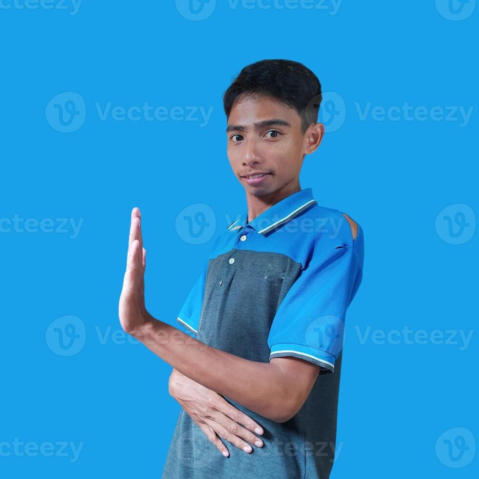 jovem ásia homem com Pare mão. com uma sério face vestindo uma azul camiseta, isolado em uma azul fundo foto