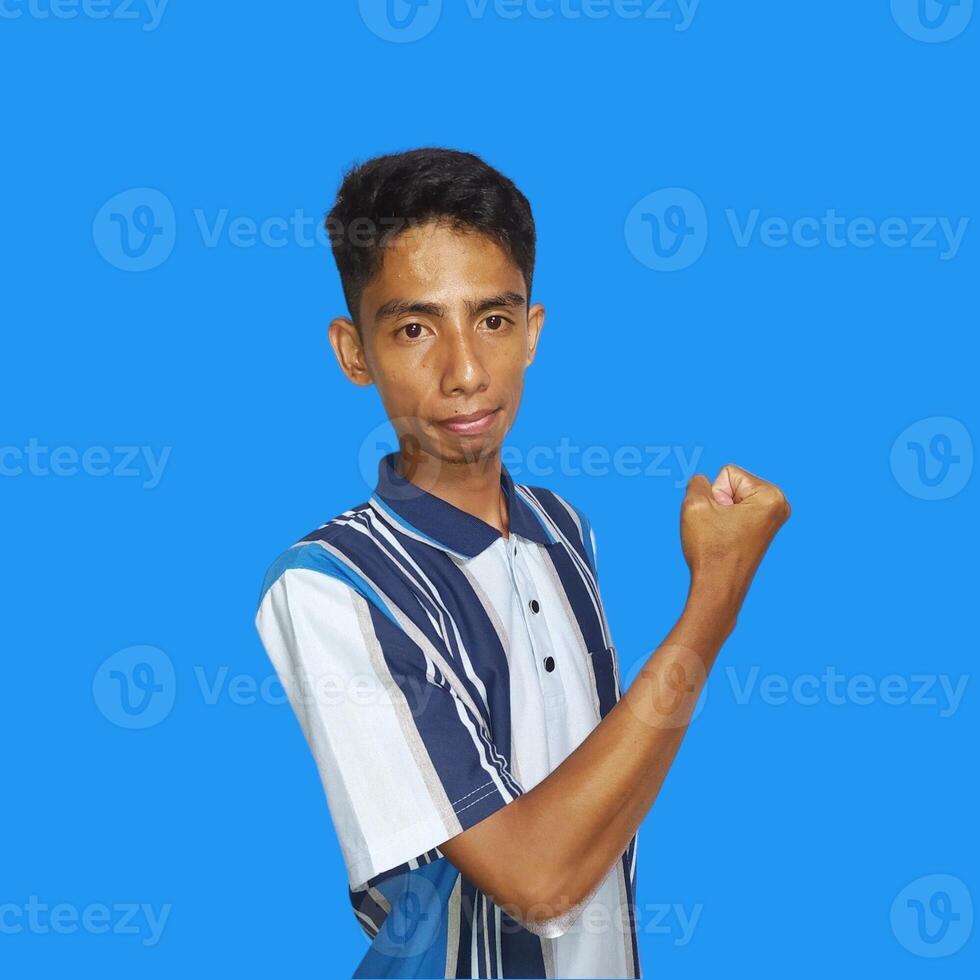 animado ásia homem vestindo colorida camiseta mostrando Forte movimento levantando braços azul fundo. foto