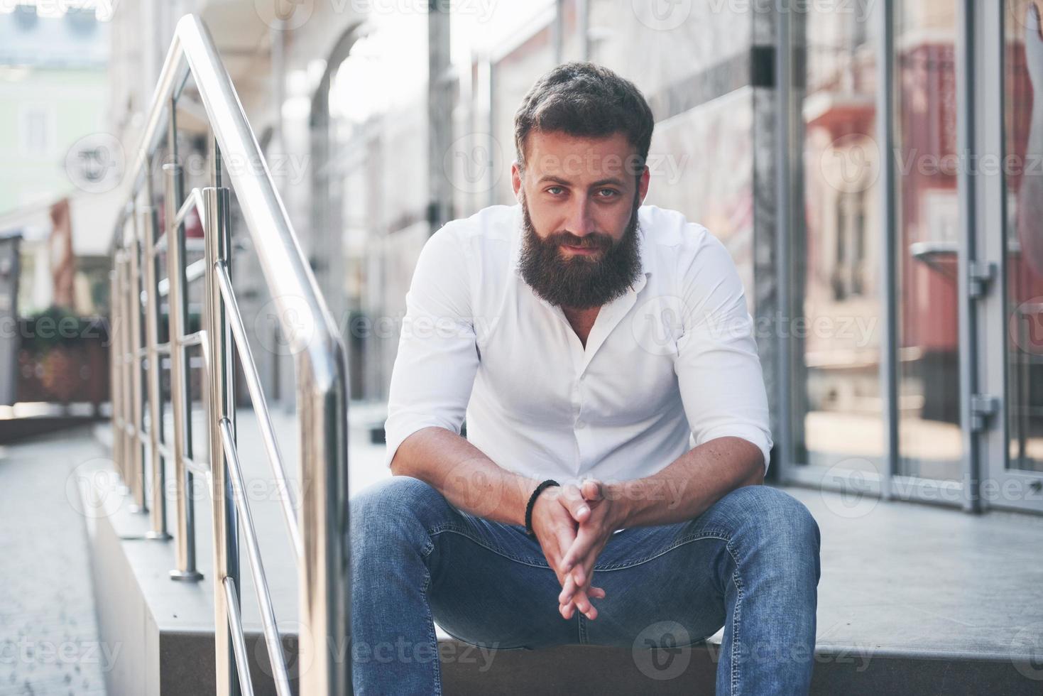 um lindo homem barbudo com roupas do dia a dia olha para a câmera. foto