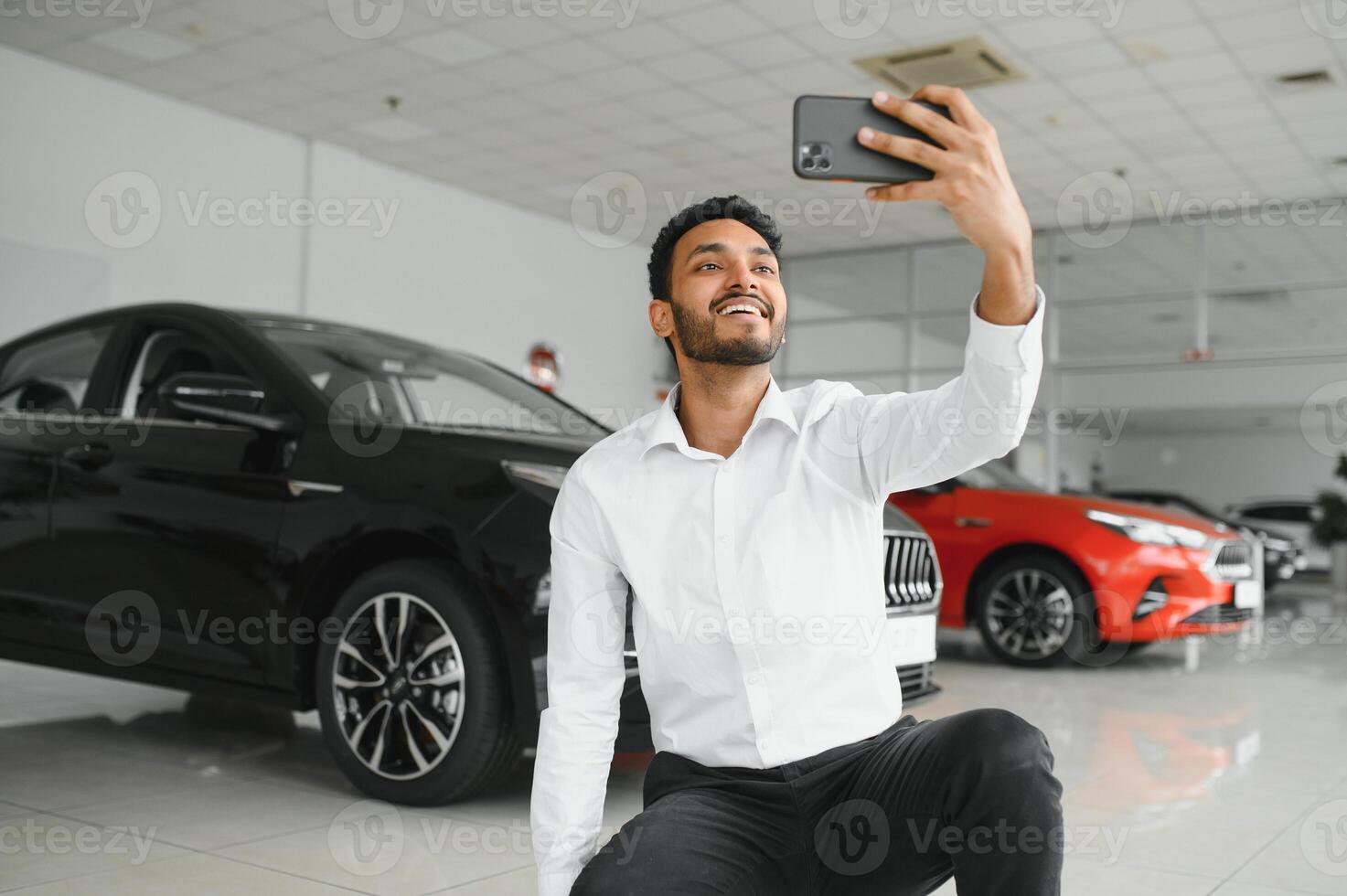 bonito indiano homem levando uma selfie com carro chaves para dele Novo automóvel às a concessionária sala de exposições copyspace tecnologia social meios de comunicação partilha positividade estilo de vida viajando turismo. foto