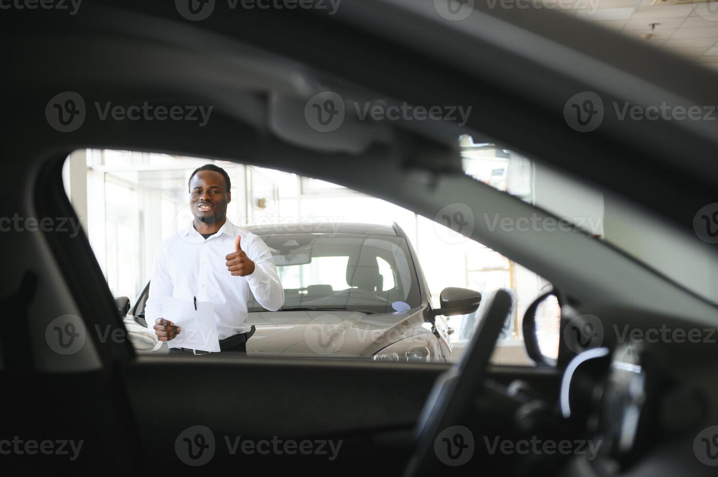 jovem africano americano carro concessionária diretor em pé dentro veículo sala de exposições foto