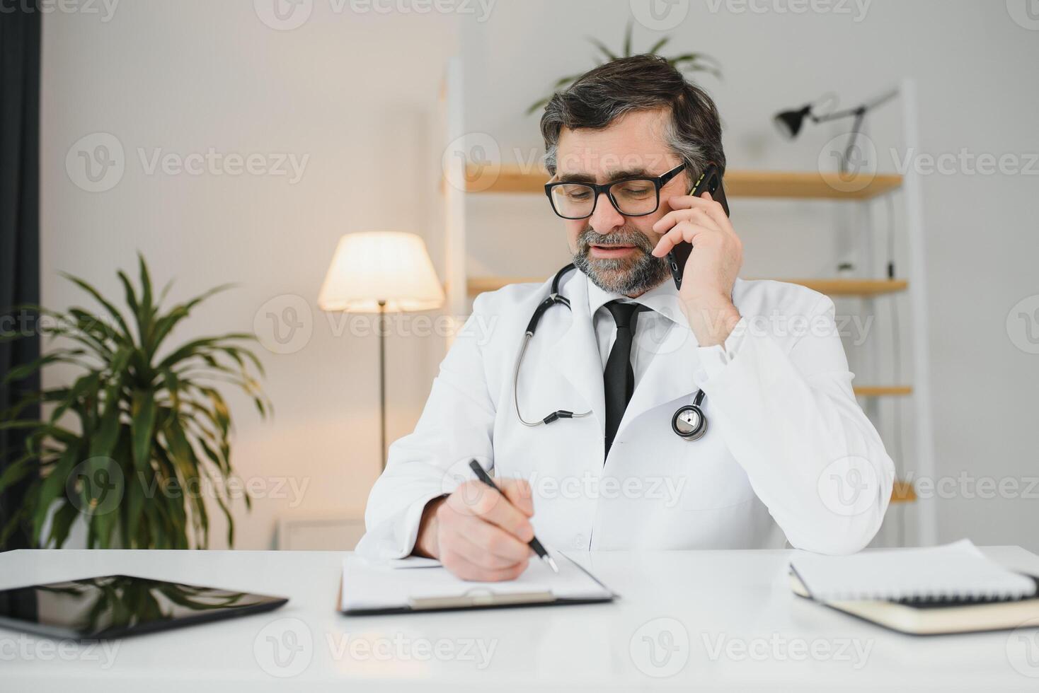 retrato do uma profissional amigáveis Senior médico usando uma Móvel telefone. foto