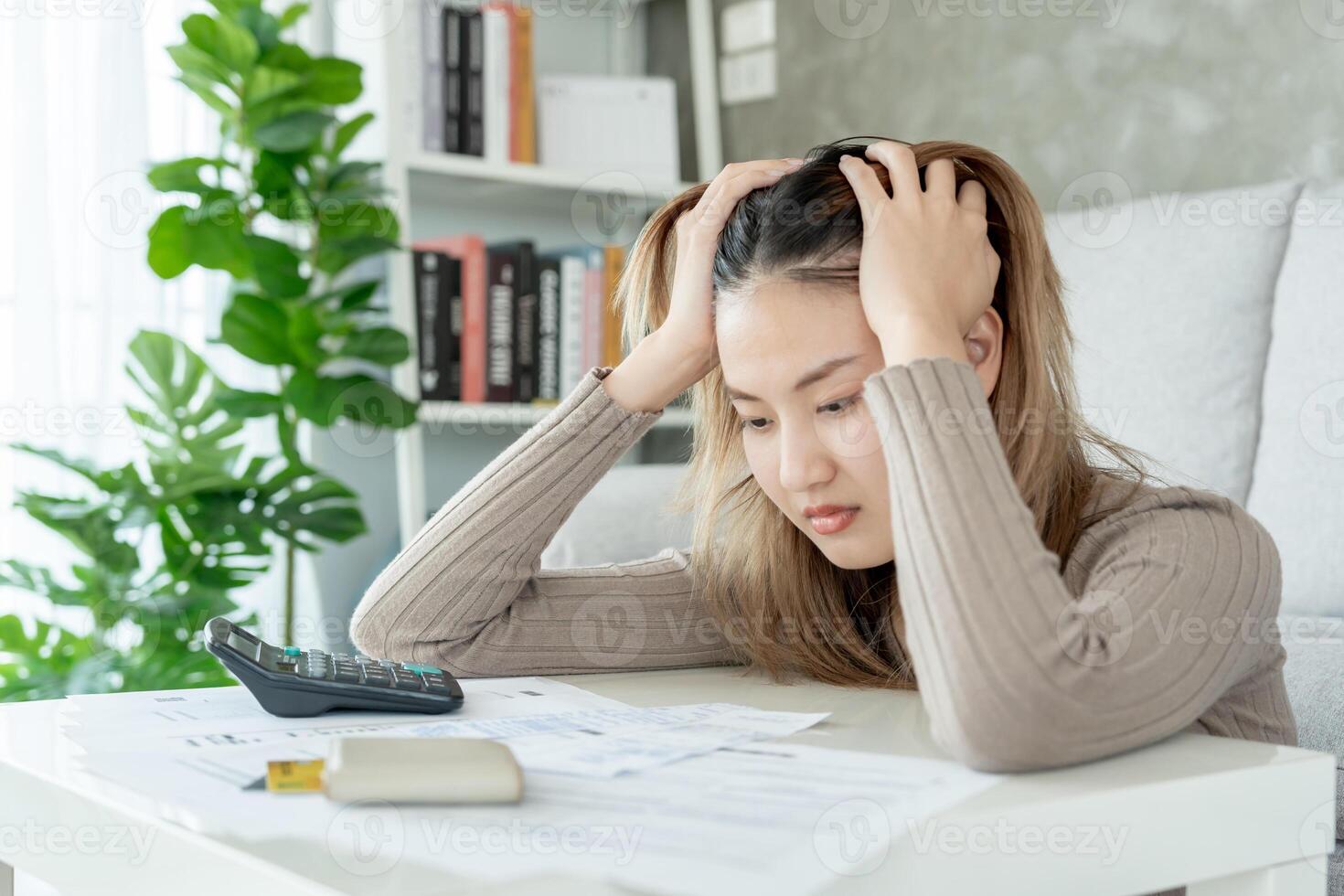 mulher asiática estressada e com dor de cabeça com grandes contas ou faturas sem dinheiro para pagar despesas e dívidas de cartão de crédito. escassez, problemas financeiros, hipoteca, empréstimo, falência, falido, pobre, carteira vazia foto