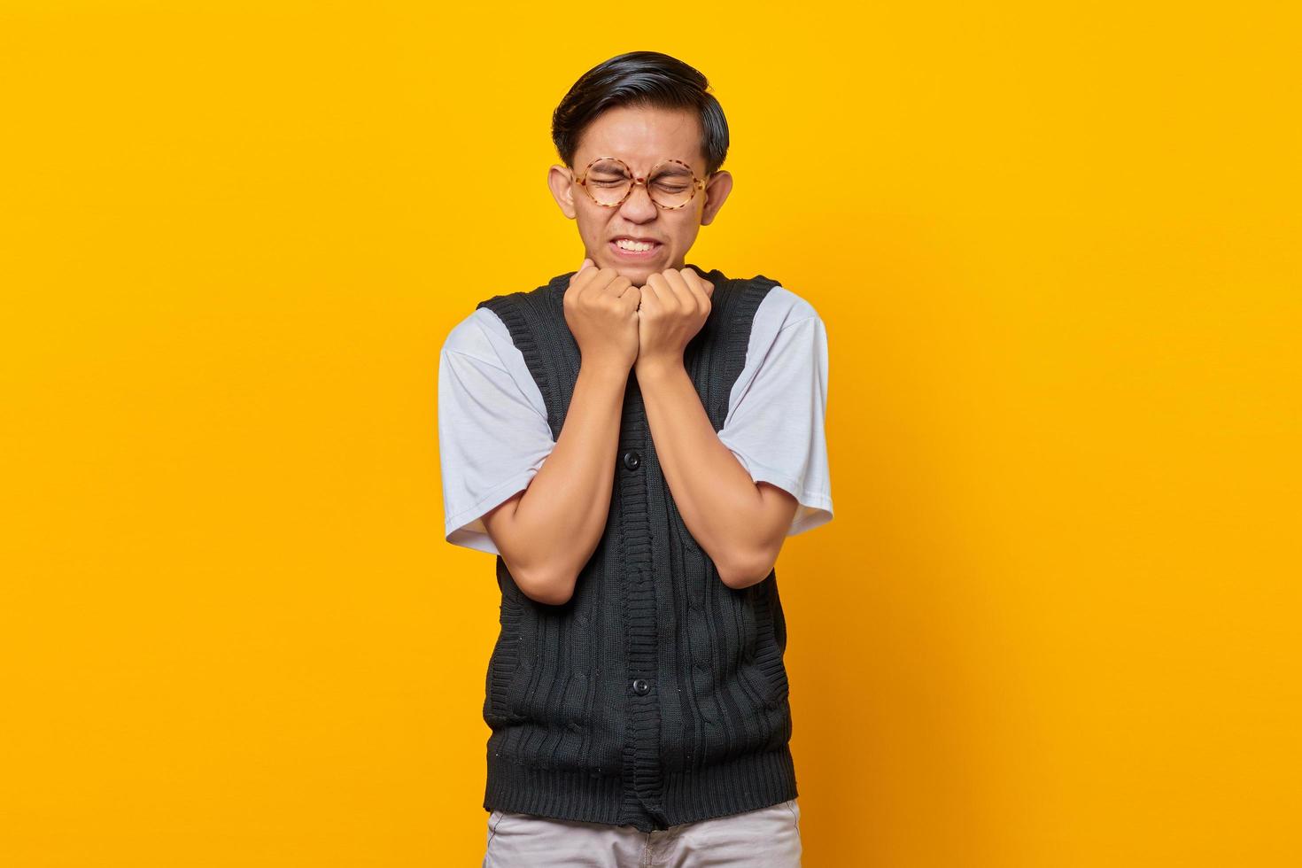 retrato de jovem asiático surpreso com a mão no queixo sobre fundo amarelo foto