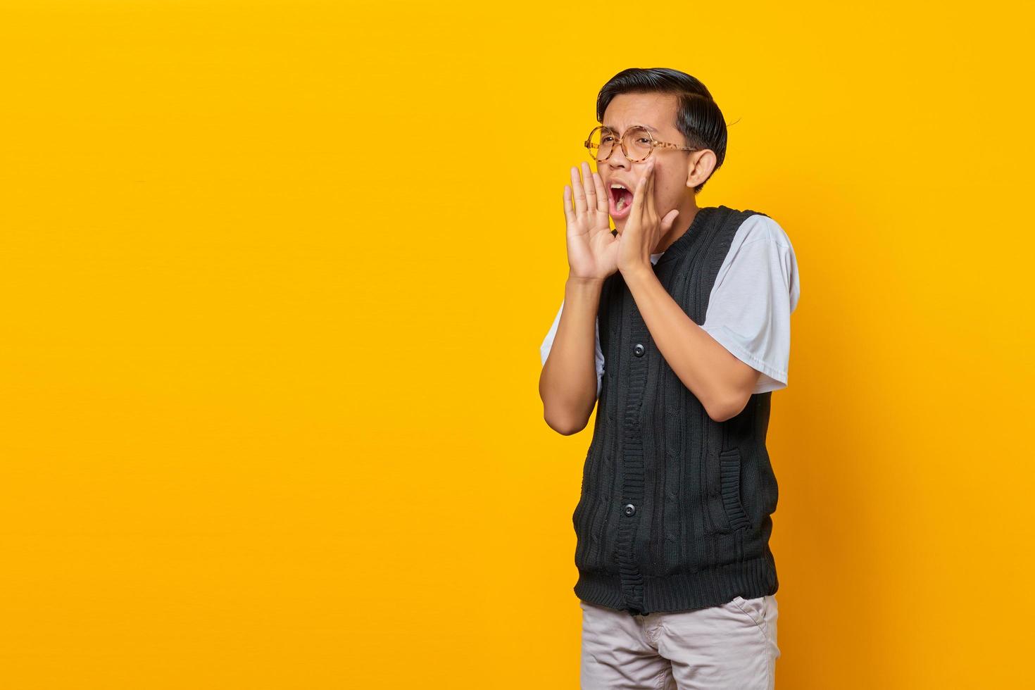 retrato de um jovem asiático gritando com uma expressão chocada em um fundo amarelo foto