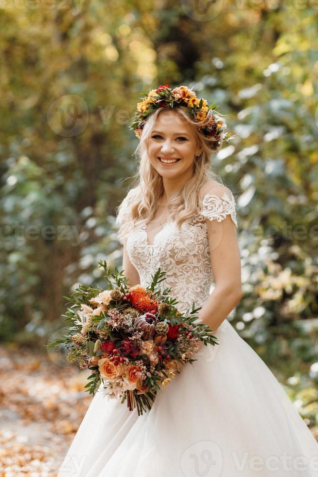 menina loira com um vestido de noiva na floresta de outono foto