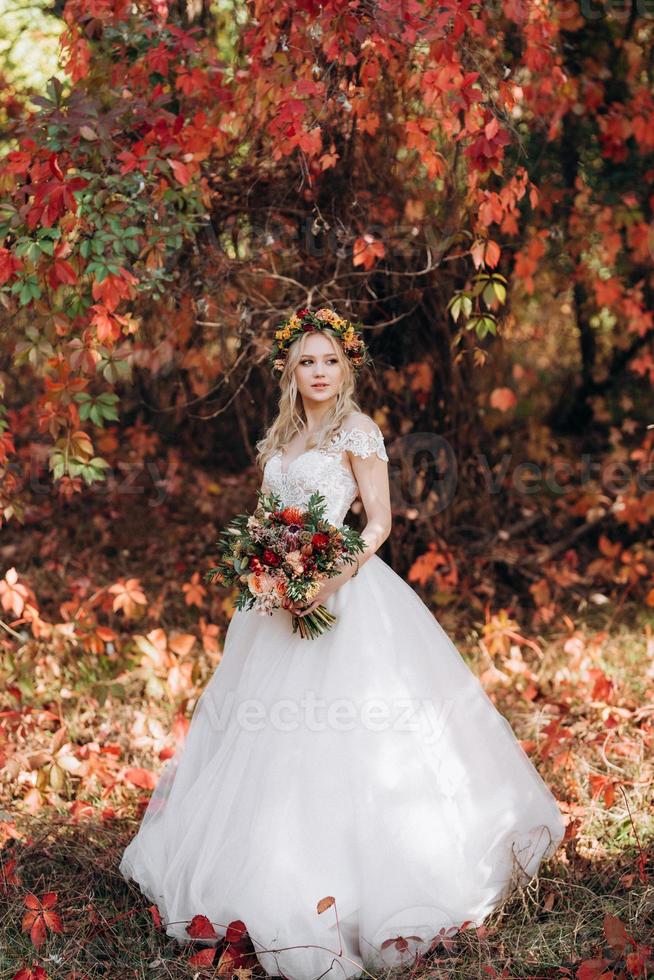 menina loira com um vestido de noiva na floresta de outono foto